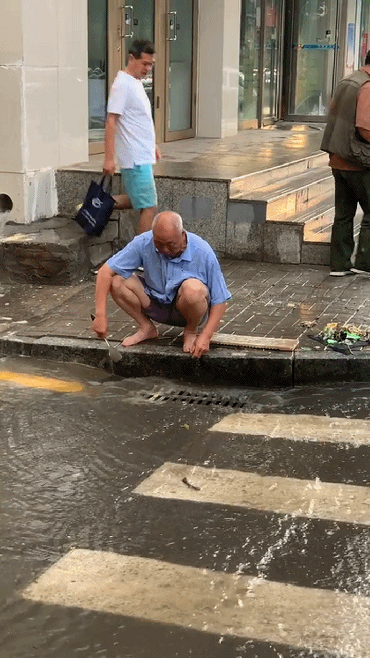 暴雨过后:大爷赤脚拿着自家的锅铲为人们疏通出一条可以走的路!