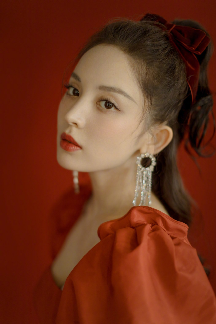 娜扎身着红色花苞袖连衣裙,头发系着丝绒蝴蝶结,同色系的精致妆容,再