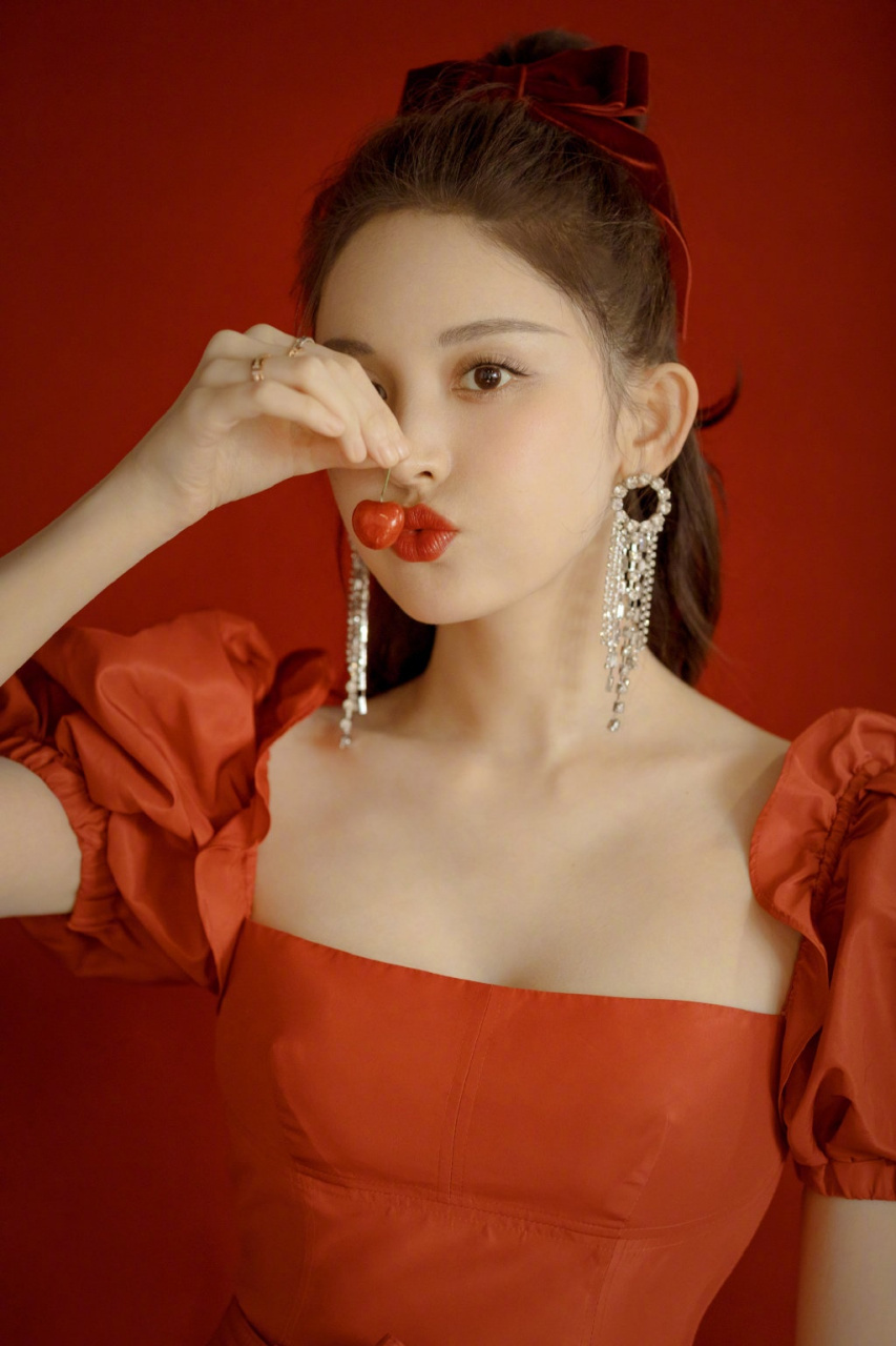 娜扎身着红色花苞袖连衣裙,头发系着丝绒蝴蝶结,同色系的精致妆容,再