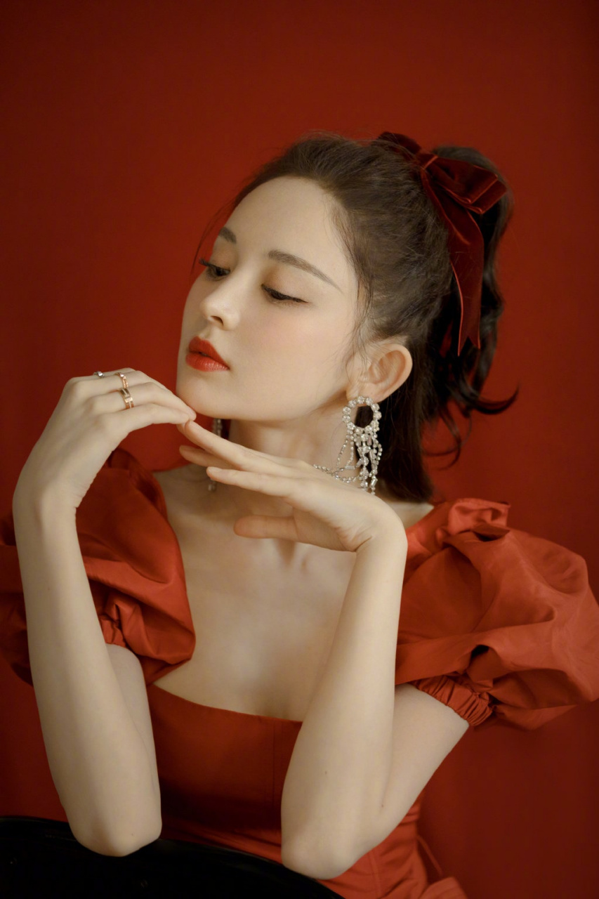 娜扎身着红色花苞袖连衣裙,头发系着丝绒蝴蝶结,同色系的精致妆容,再