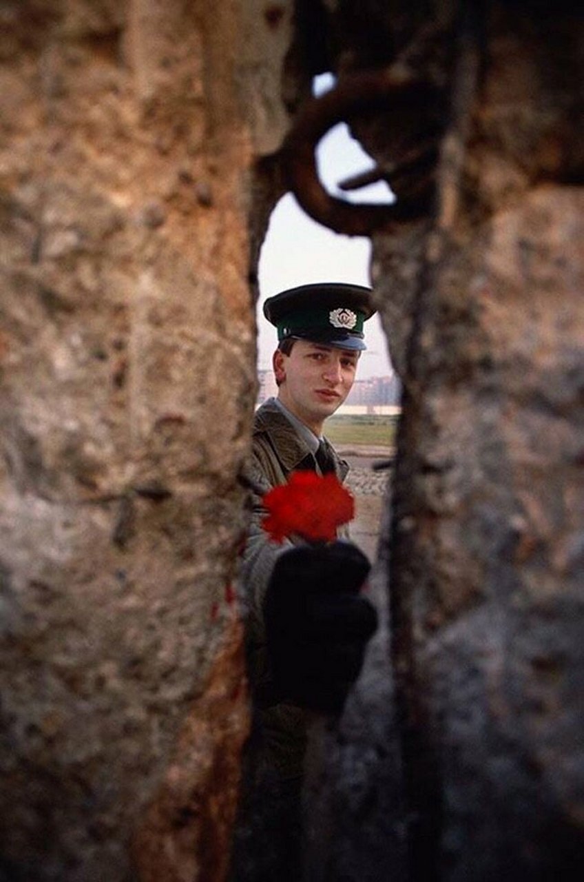 1989年,一位东德士兵从柏林墙的裂缝中向另一侧递上一朵鲜花.